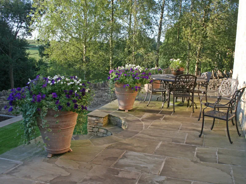 A set of Lutyens steps with two large planters either side next to a table and a set of chairs